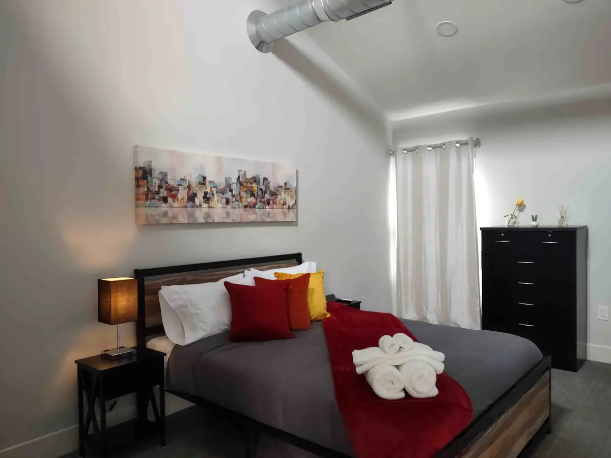 Guest bed with a red throw and white towels folded into swans, ready for check-in