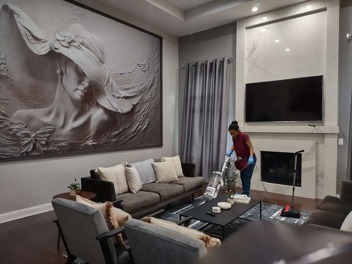 A Dunlap cleaner vacuuming a living room with a marble fireplace wall