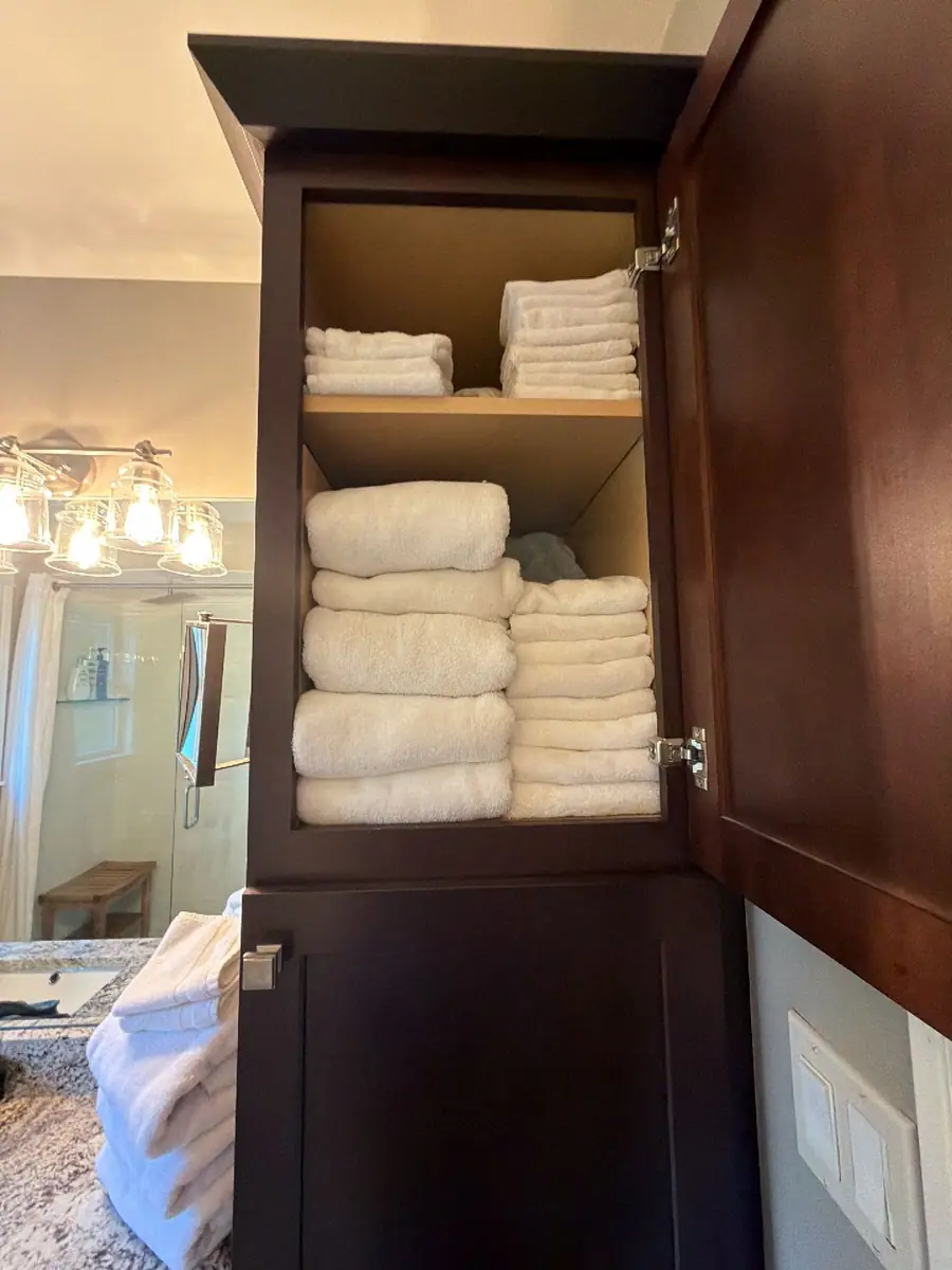 Linen cabinet stocked with neatly folded white towels
