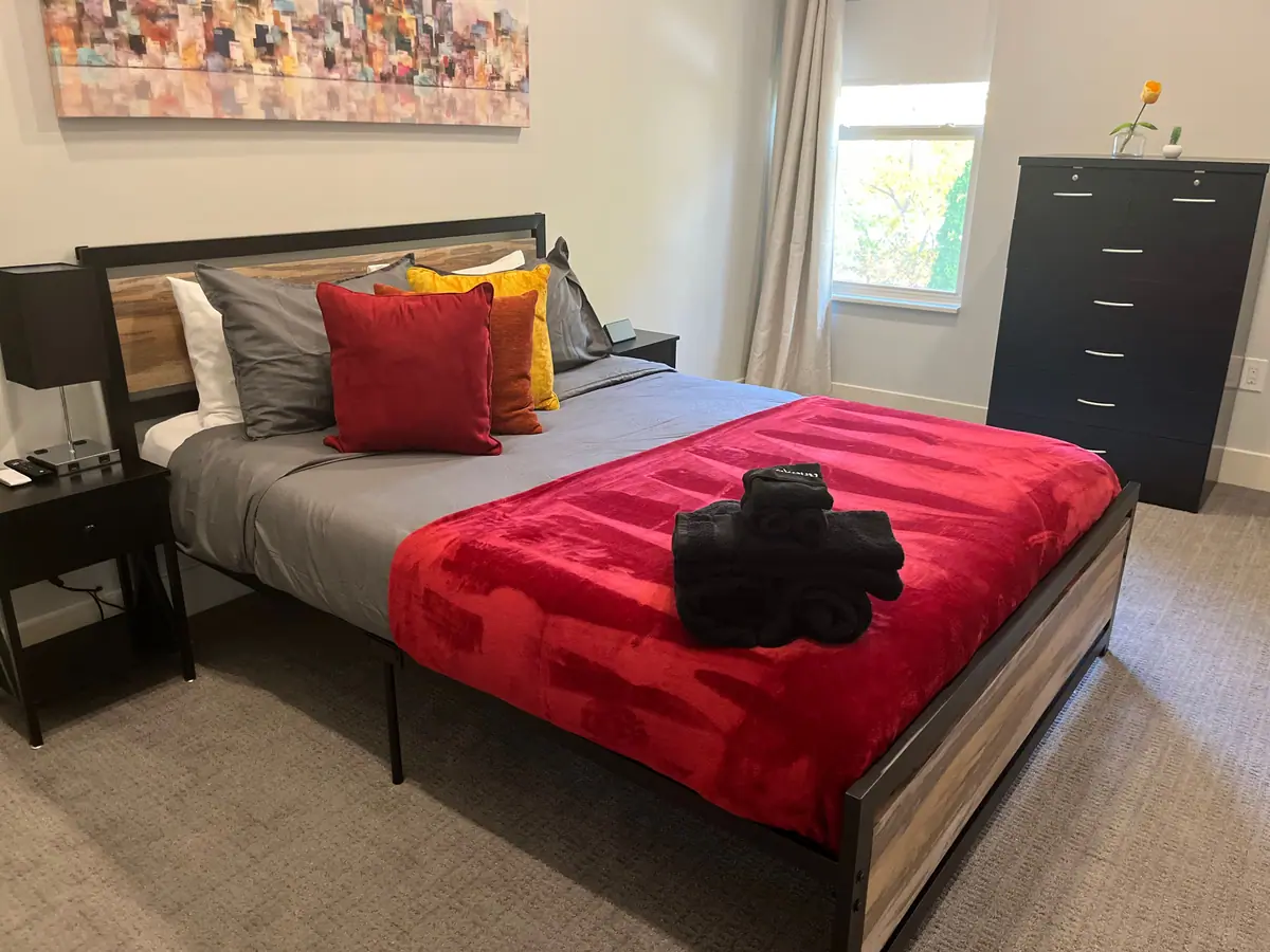 Guest bed made with a red blanket and towels set out