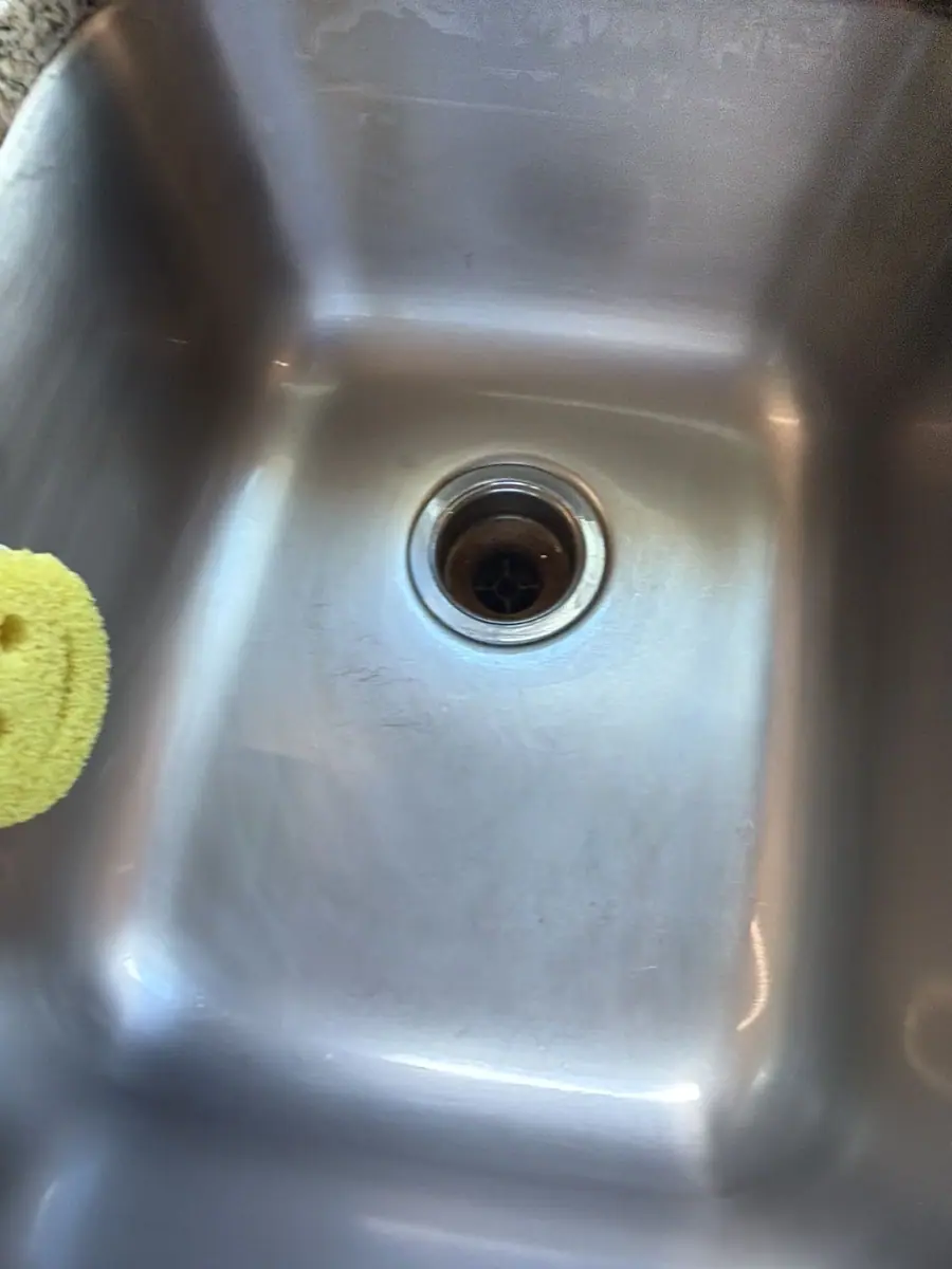 A stainless basin mid-scrub, sponge in hand