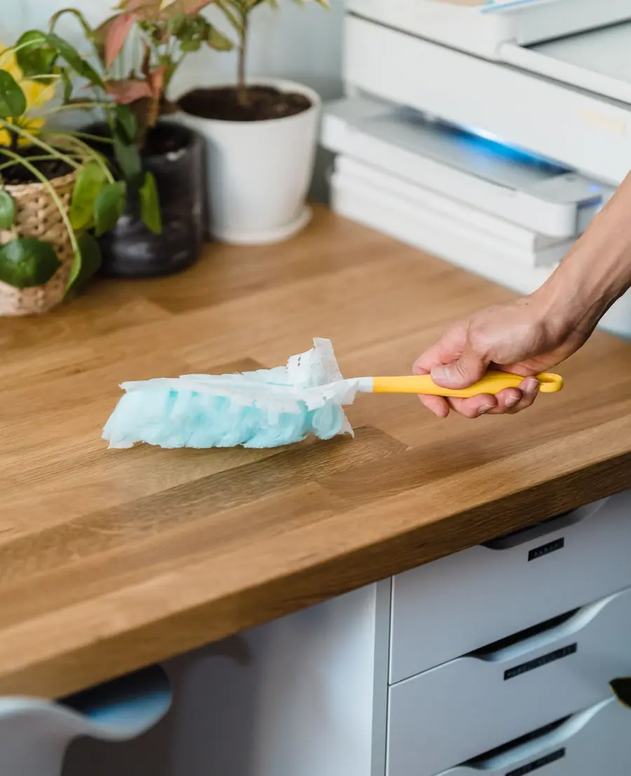 Hand dusting a wood desk with a yellow duster (stock photo)