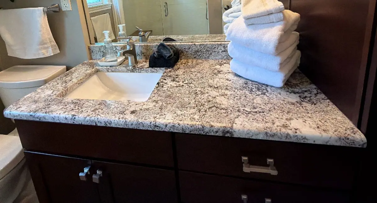 Granite bathroom vanity with a stack of fresh white towels